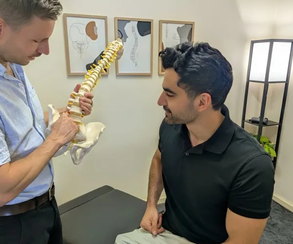 Dr Simon Hardy explaining findings to a patient using a spine model at Bassendean Chiropractic